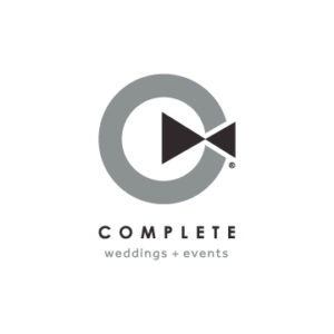 Complete Weddings and Events Logo is a grey circle with 2 black triangles on the right side, pointed towards the center of the grey circle.