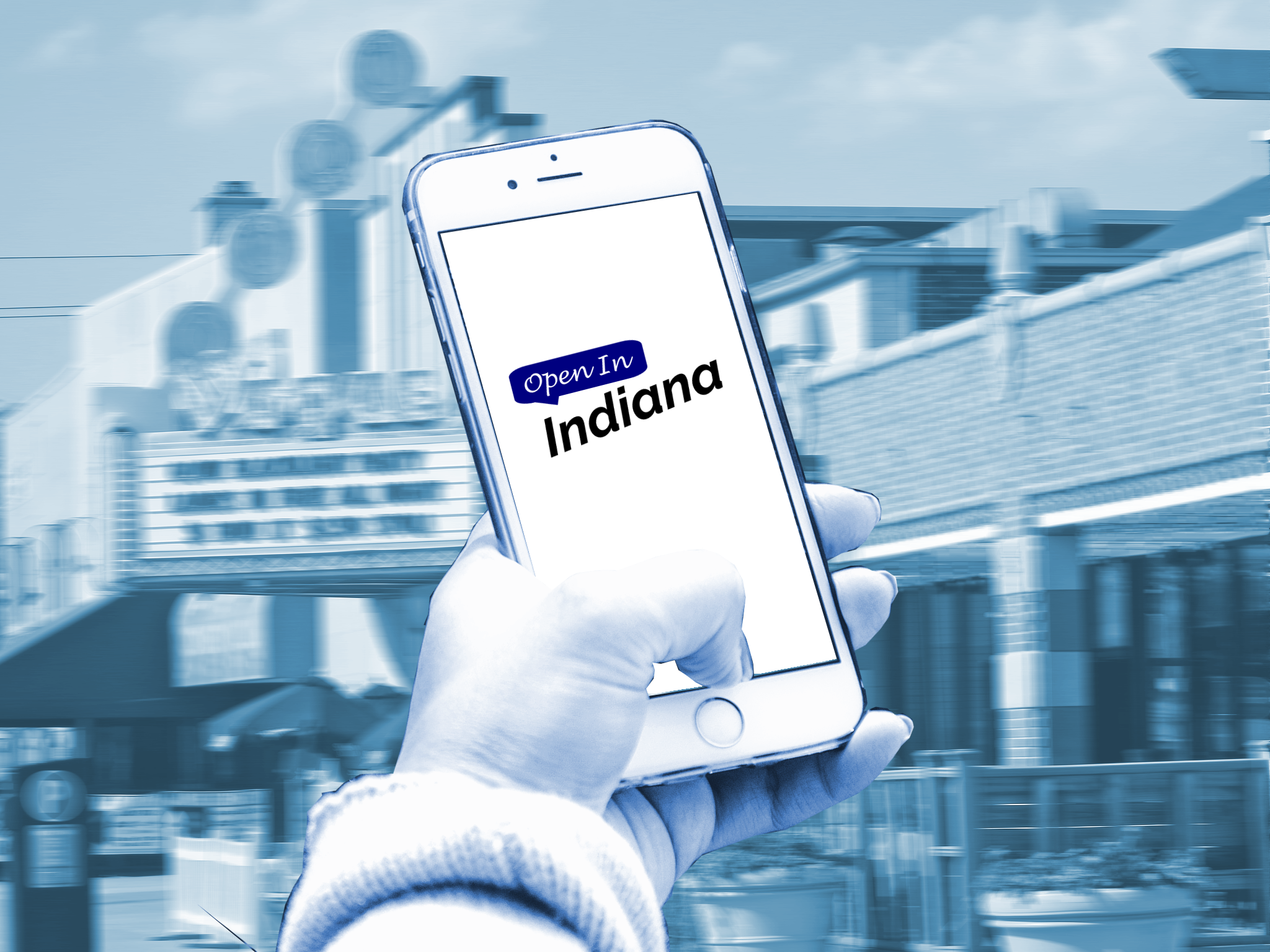 A person holding a smartphone with the Open In Indiana logo on it, in front of the strip in Broad Ripple.